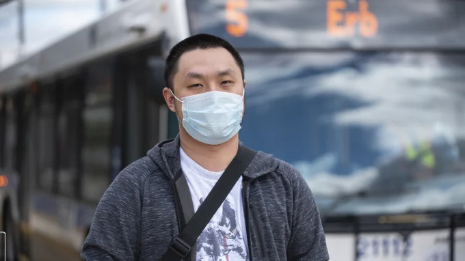 Man wearing mask in front of GRT bus