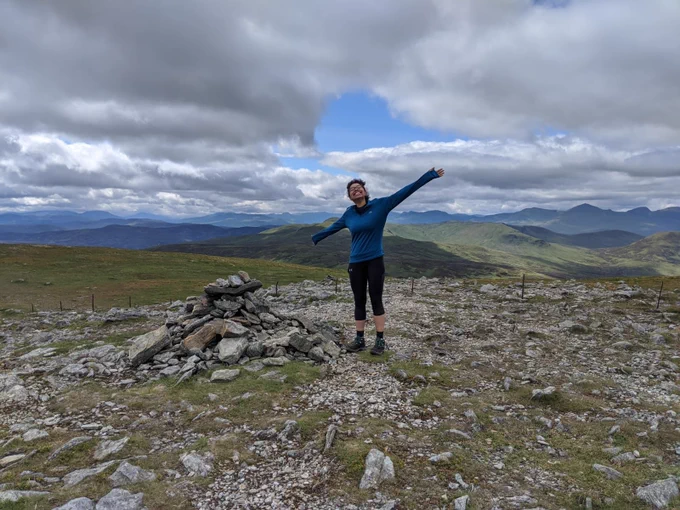 Jade at the top of the Munro (Scottish mountain), Ben Chonzie. Arms spread out wide, big smile!