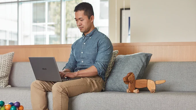 Photograph of a man using his laptop for work at home.