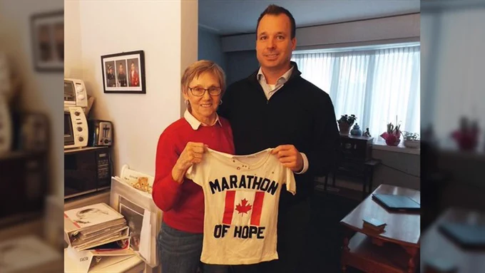 Joanne and Brendan Dineen in Joanne's St. Agatha home, with the t-shirt Brendan made for his first Terry Fox Run. Photos of Brendan's son, Jameson, are on the wall behind them. - Nigel Gordijk photo