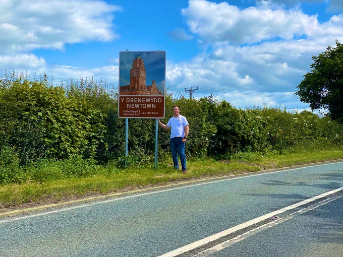 Stu Trigg of @DragonUAV Digital Media next to his photograph on the new sign