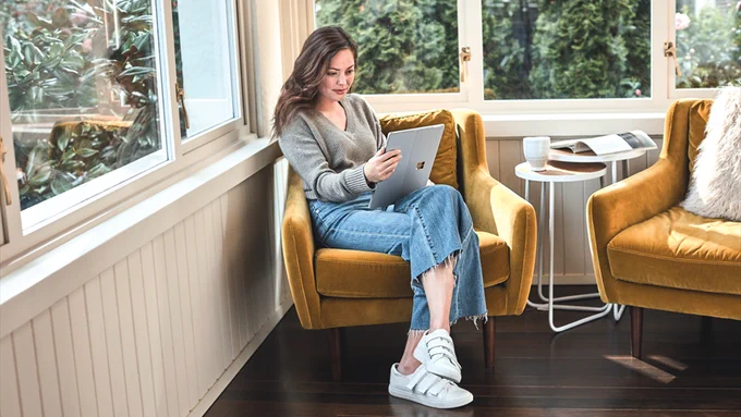 Photograph of a woman using her laptop to work from home in a comfortable setting
