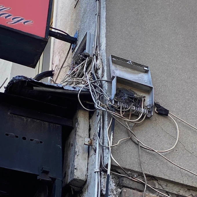 Boitier de raccordement cuivre sur facade, ouvert, avec des cables qui pendent.