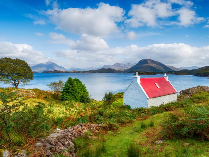 Red-roofed house with white-washed walls looking out to sea and across to mountains in Applecross