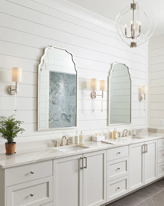 Savoy House Fremont sconces hang beside bathroom mirrors and an Epsilon pendant hangs overhead.