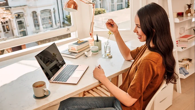 Photograph of a woman taking a work meeting at home, using her laptop.
