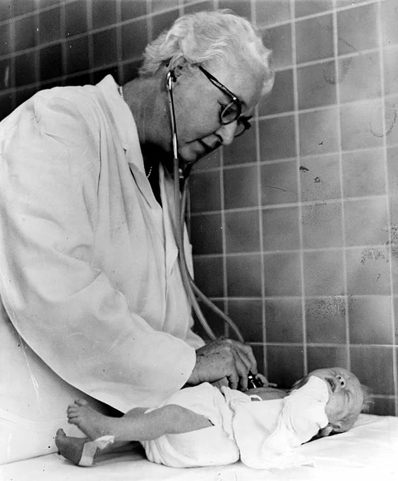 Virginia Apgar, creator of the Apgar score using a stethoscope on the chest of a baby