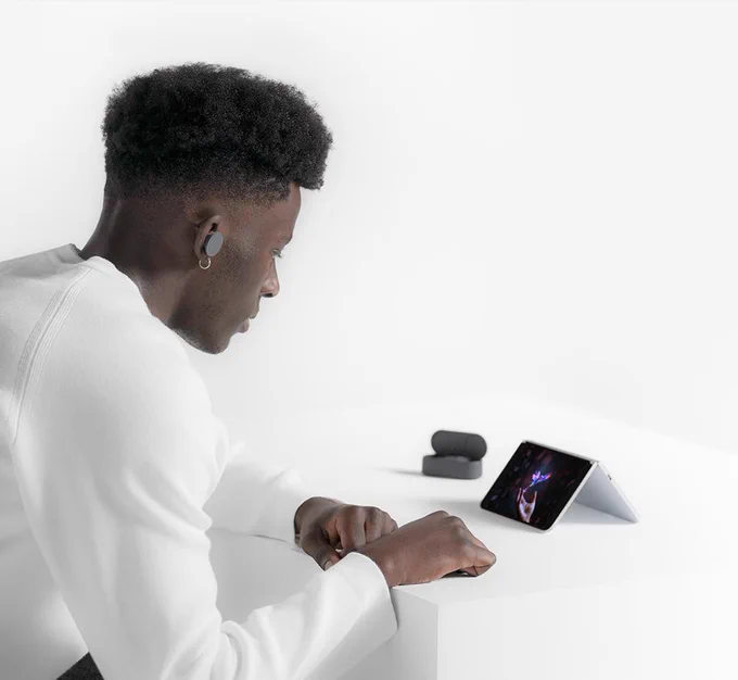 A man watching a video on Surface Duo with Surface Earbuds.