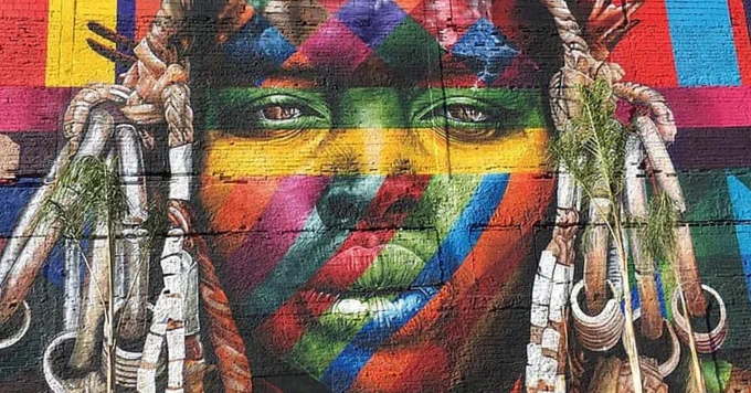 Colorful painting of a woman's face on the side of a building.