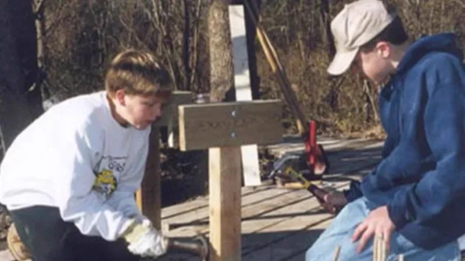 Two Scouts hammer nails on a deck.