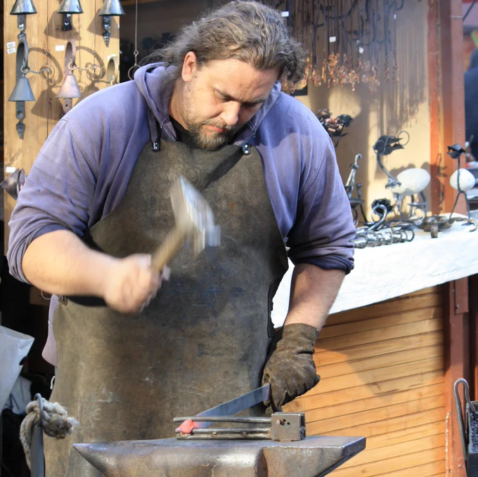 Modern blacksmith at work, beating hot metal on an anvil