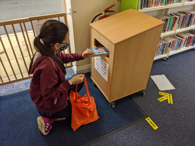 Lucy returning her books in the returns box at Thirsk Community Library.