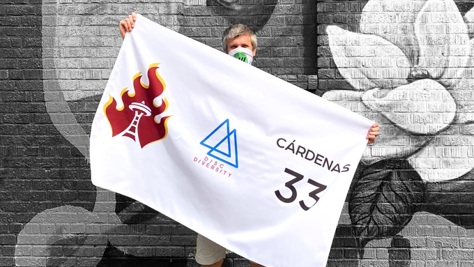 Todd Curran, CEO of XII Brands, holding a banner representing a BIPOC player with their name, number, and team logo.