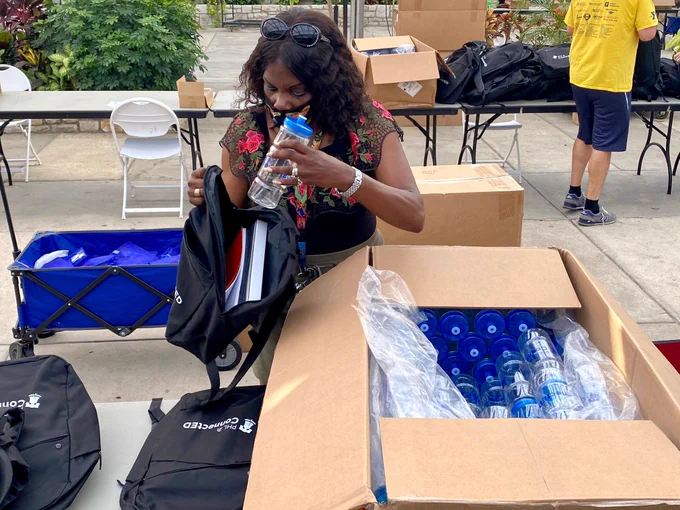 Volunteer puts a water bottle inside a backpack