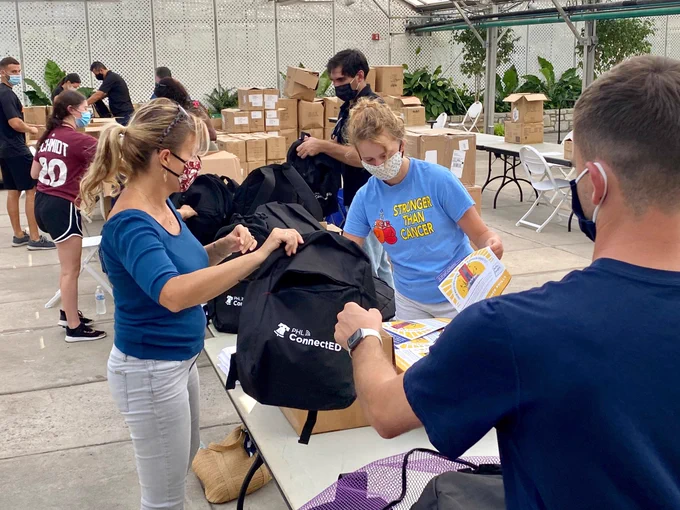Volunteers wearing masks assemble backpacks