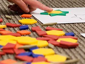 Child's finger arranging colored shapes