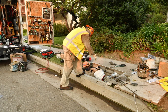 Image of utility worker peering down an underground vault. 
