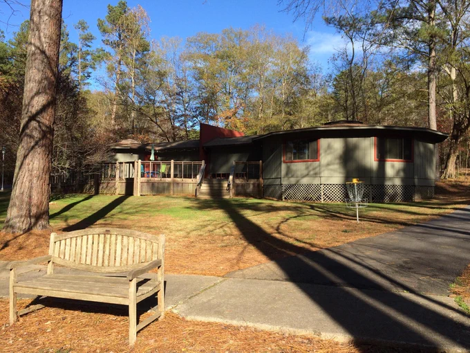 A bench in front of a lawn and building at the Clemson University Outdoor Lab.