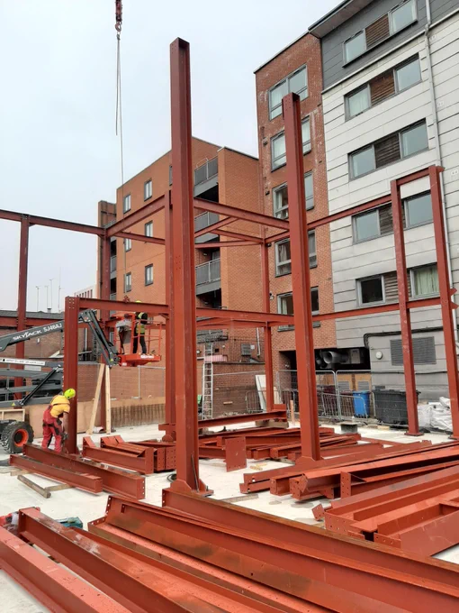 2 Construction Workers build the orange steel frame of the the new Manchester LGBT  centre rebuild