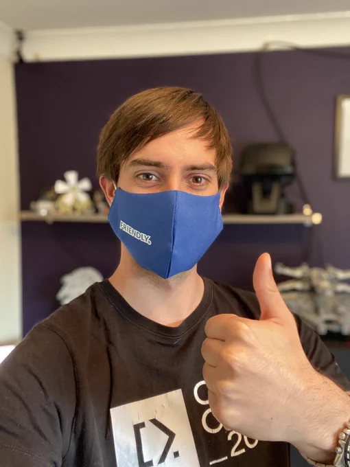 Mike smiling, with a thumb up wearing a blue face mask with the word friendly on it from Umbraco