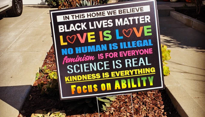sign states: In this home we believe, black lives matter, love is love, no human is illegal, feminism is for everyone, science is real, kindness is everything focus on ability