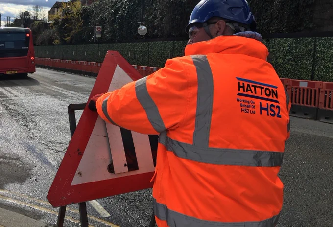 A road worker erects road direction signs at a road works site