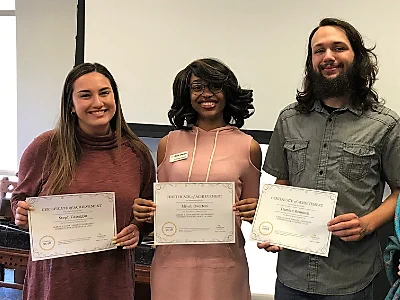 3 Students holding certificates