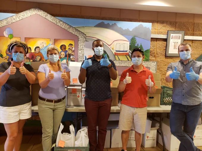 Five people wearing surgical masks and gloves are giving a thumbs up.