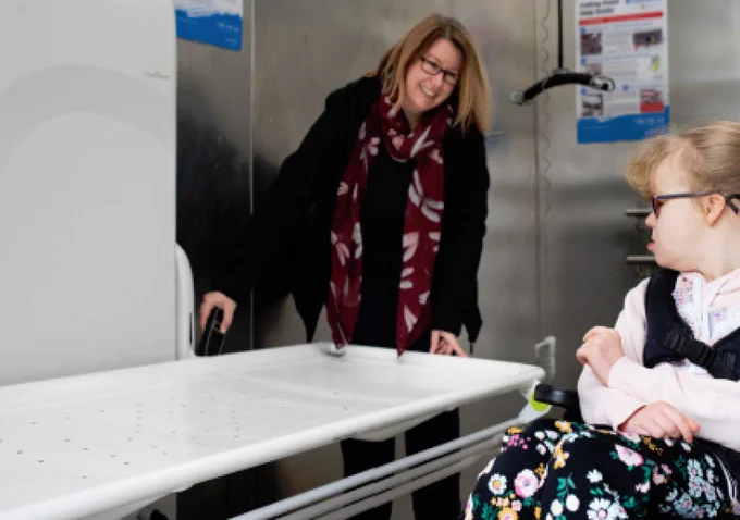 Moeder en dochter bekijken de verzorgingstafel in een changing place.