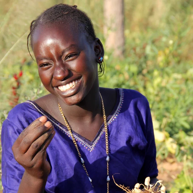 Teenager holding beans and groundnuts during the harvest season.