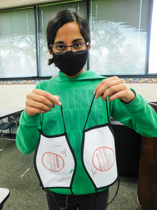 Girl holding several custom masks with the Pacer logo