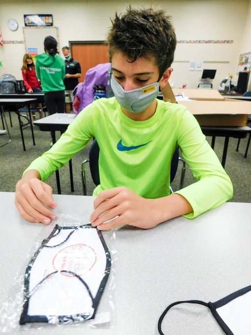 Boy placing a custom mask into a bag