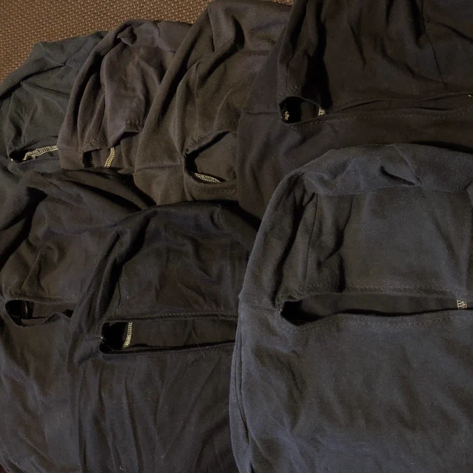photo of seven black balaclavas sewn from old t-shirts, lying flat