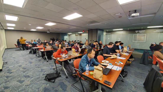 Group of individuals sitting in an office meeting space, classroom style, while hacking at CMD CTRL.