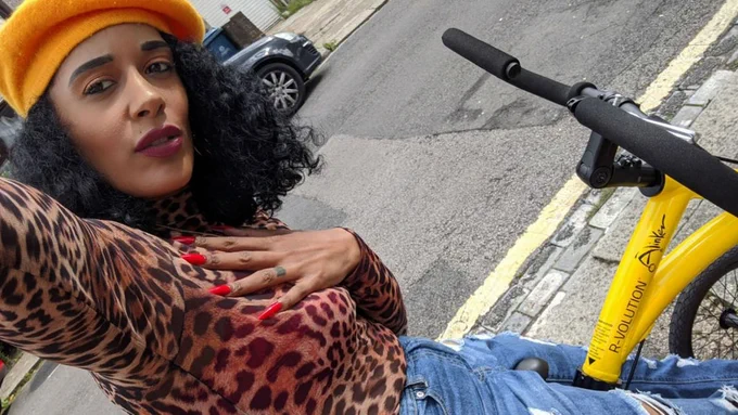 Image shows Roxanne sat on a bicycle and taking a selfie