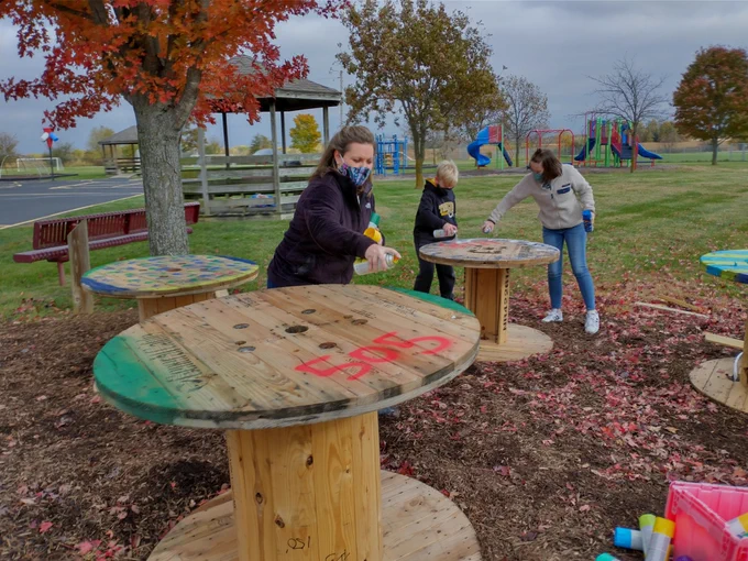 Teachers and student work to spray paint tables