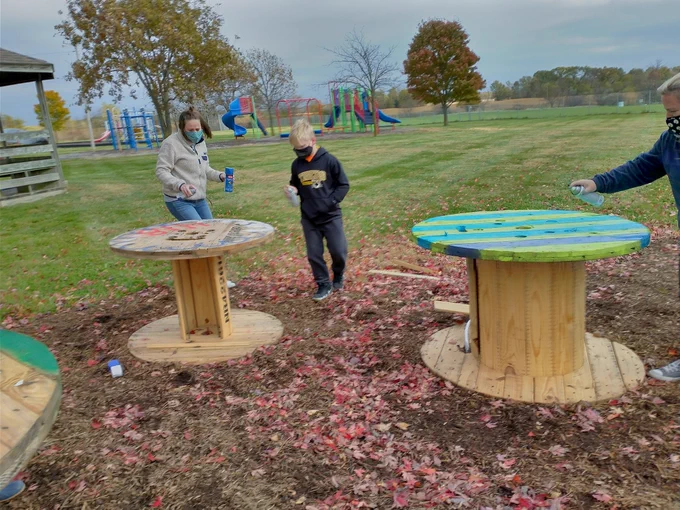Teachers and students work on spray painting tables
