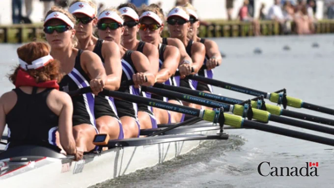 Image showing a Canadian women's 8-person canoe-kayak team rowing at a competition.
