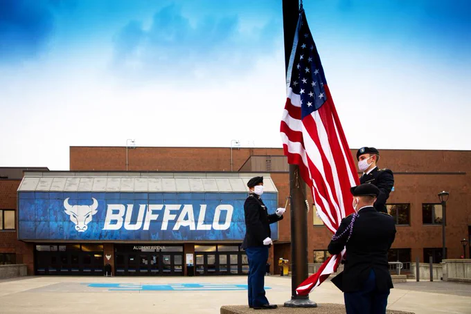 Three people in military dress raise the American flag.