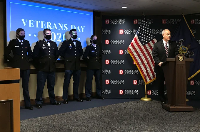 Don Accomando, right, welcomes the online audience to the 22nd Annual Veterans Day Breakfast, hosted by Duquesne University. Members of the Duquesne ROTC are at left.