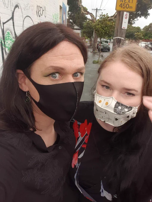 Selfies of girlfriends with masks on taken outside after it's been raining. One looks happy the other which is me looks cross