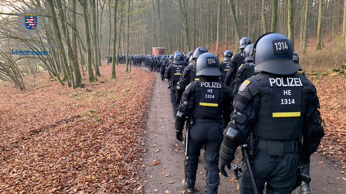 Polizeikräfte auf dem Weg in den Wald in Schutzausstattung mit Helm und Körperschutz.
