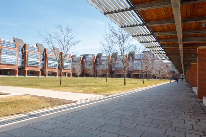 Polonsky Commons in the early spring. The trees are still bare and the grass has a yellow tinge to it. The sky is blue with very few clouds. 