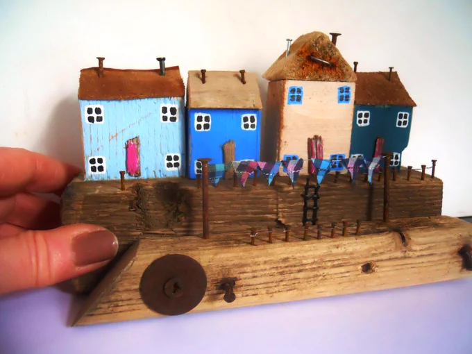 Miniature scaled houses, hand crafted to reflect seaside quayside scenes with bunting, step ladders, flags, rusty railings