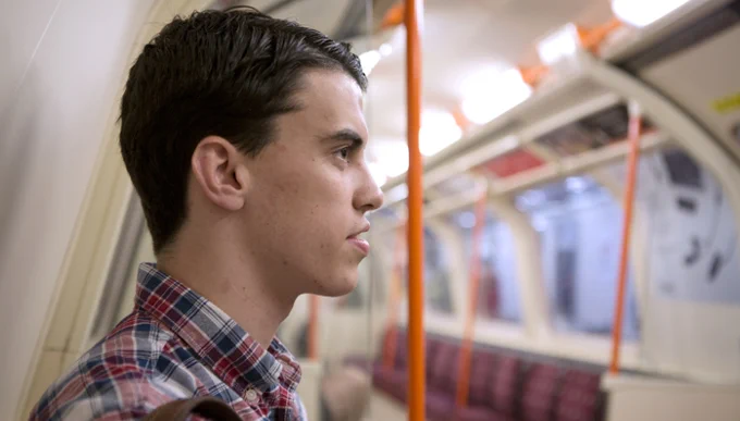 Side profile of a man sat on the London Underground.