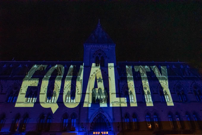Illuminated message on the facade of the Oxford Museum of Natural History saying Equality in cream letters on blue background