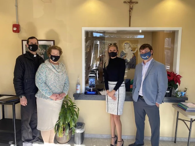 two staff members of St. Dominic's Catholic School receive Temperature Kiosk from Two RJ Young employees