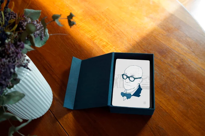 Fotografía de la tarjeta de Le Corbusier, con ilustración y dentro de una caja de cartón con logo en oro.