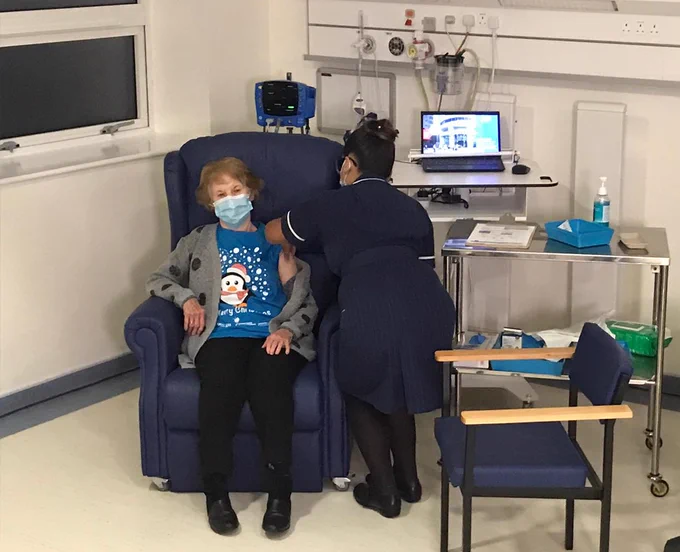 Maggie receiving her COVID-19 vaccine from member of staff at University Hospitals Coventry and Warwickshire NHS Trust.