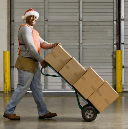 warehouse worker in santa hat transporting boxes